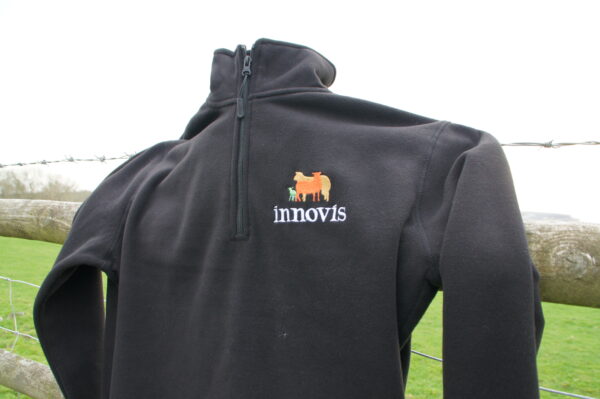 An Innovis branded fleece hung on a livestock farming wire fence
